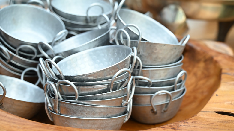 Small aluminum bowls stacked in a large wooden tray