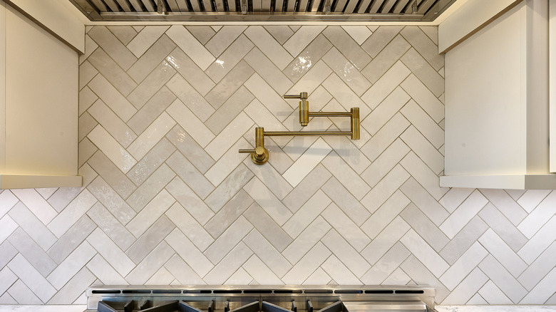 White subway tiles laid in a herringbone pattern above a stove