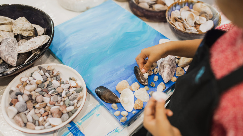 Person making a piece of art with seashells and rocks
