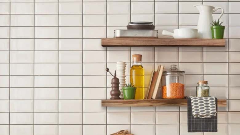 The acacia wood floating shelves on a white tile wall.