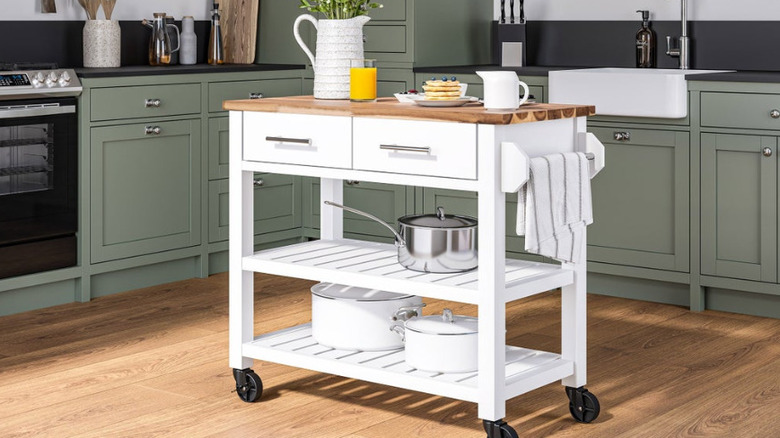 The white rolling kitchen cart in the center of a modern kitchen.