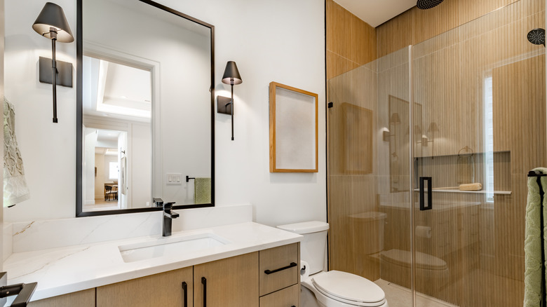 Neutral bathroom with white marble countertop, wood vanity and large mirror