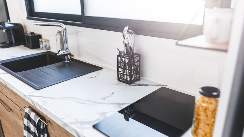 Kitchen with marble adhesive counter, black sink and stainless steel fixtures