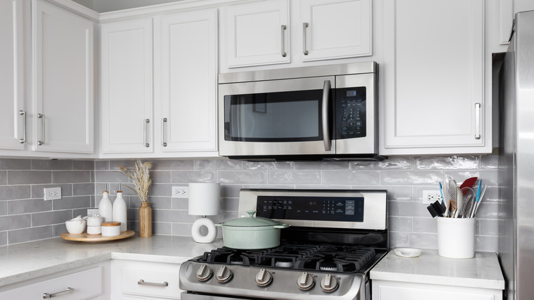 White kitchen with white cabinets and countertops, grey backsplash