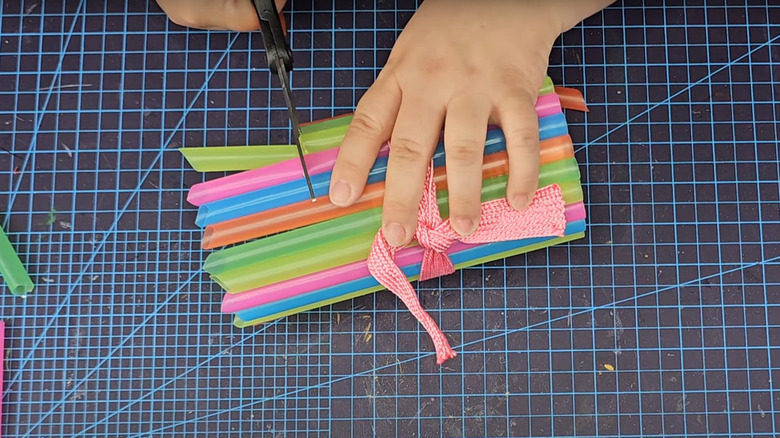Woman cutting straw planter with ribbon on cutting mat