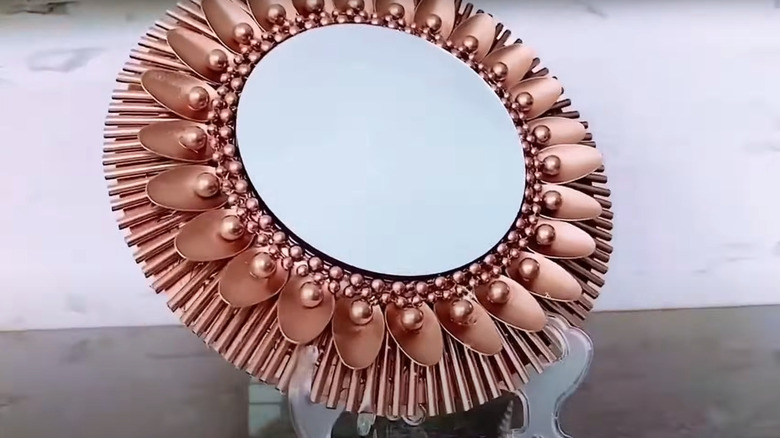 Stylish bronze mirror made of spoons and plastic straws