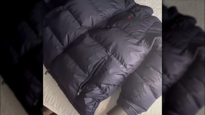 person using hair dryer in sleeve of puffy jacket to fluff insulation