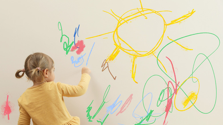 girl drawing on wall with crayons
