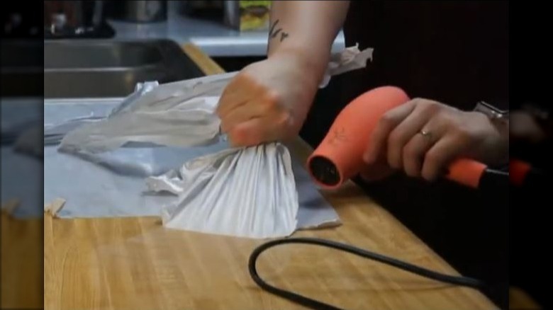 person removing contact paper from counter with hair dryer