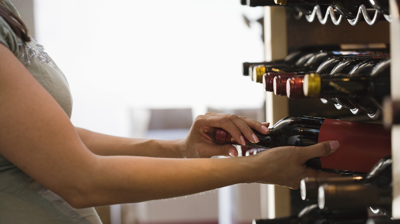 Woman getting bottle of wine from rack