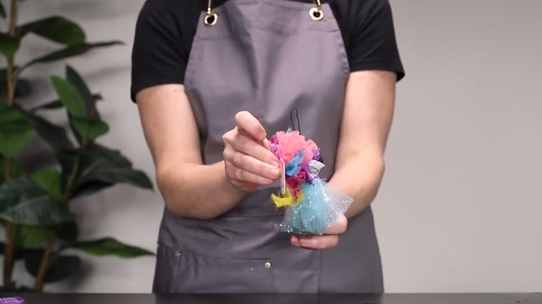 Person in apron holding cinnamon broom decorated with tulle like a fairy