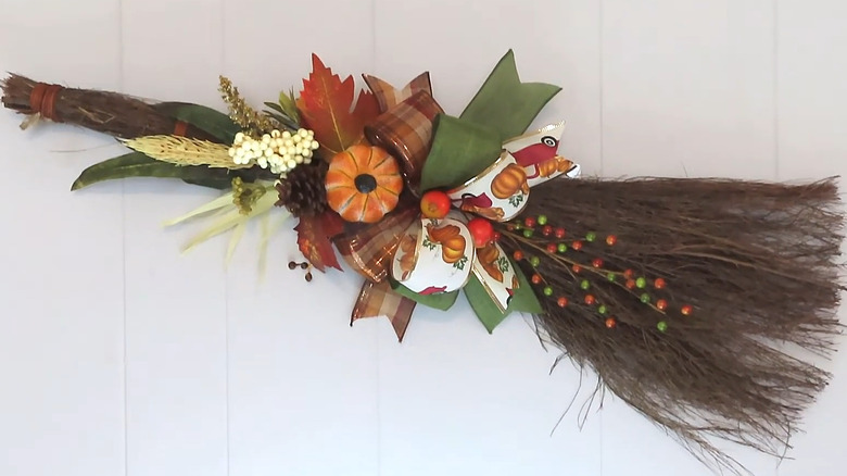 Cinnamon broom decorated with fall florals, pumpkins, and bows