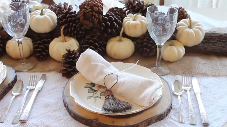 Woman at table with broom centerpiece with pinecones and mini pumpkins