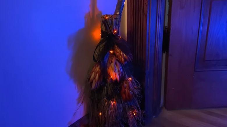Cinnamon broom decorated with orange lights and flowers to make a witch's broom