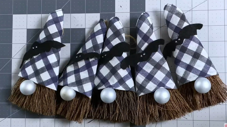 Gnomes made from cinnamon brooms, lined up on a craft table