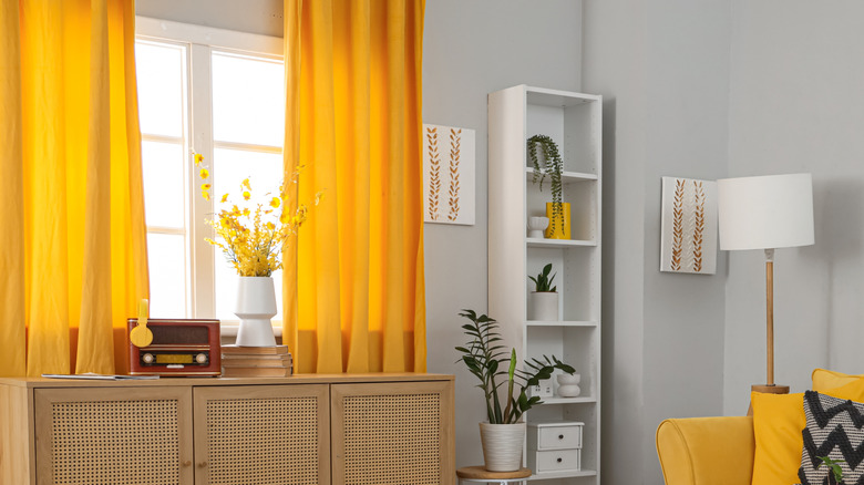 A light gray-walled room with bright yellow curtains and white and black decor.