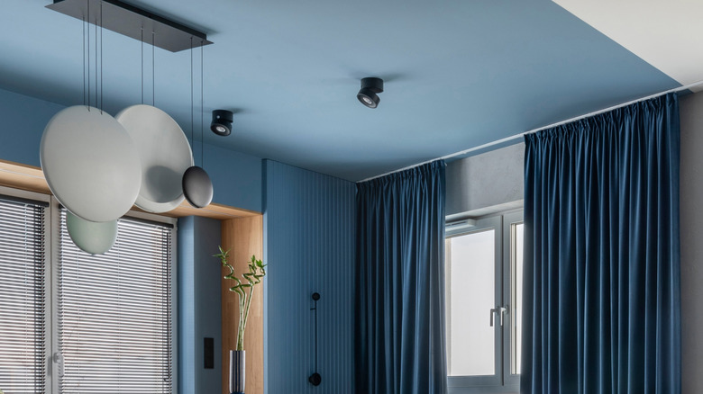 A living room in shades of blue, gray, and natural wood with slightly darker blue curtains.