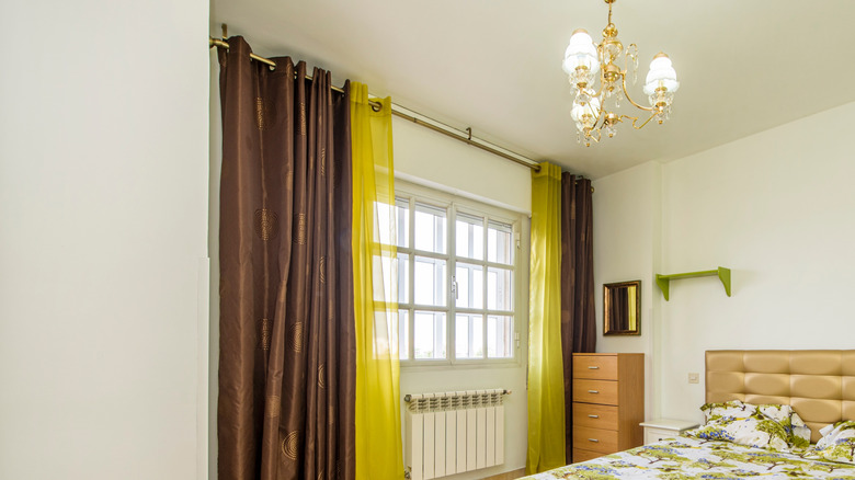 Green and brown curtains covering up a whole section of wall and window in a bedroom with a similar color scheme