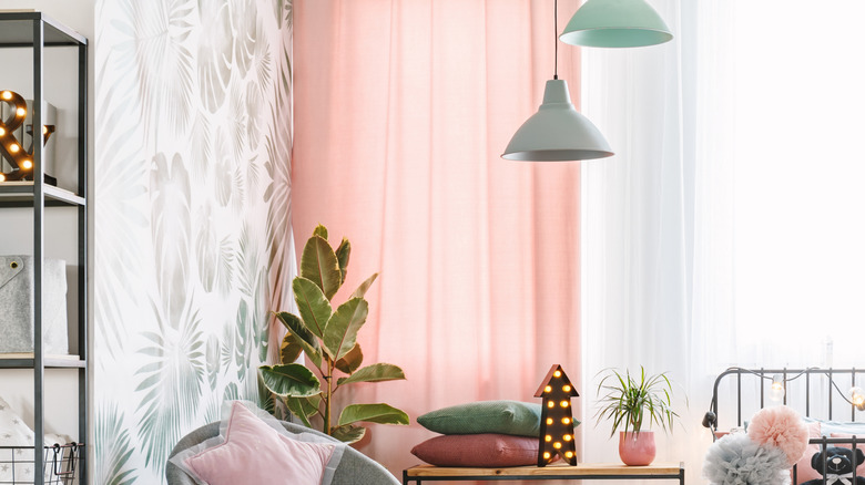 A bedroom with pink curtains and green-and-white patterned wallpaper.