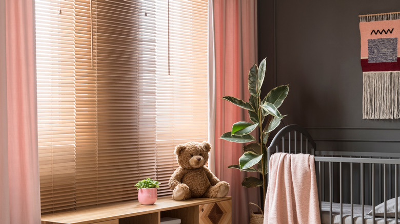 A dark gray nursery with pink curtains and dark gray walls.