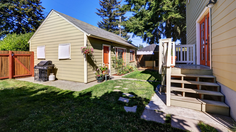 A granny flat behind a larger house in the backyard.