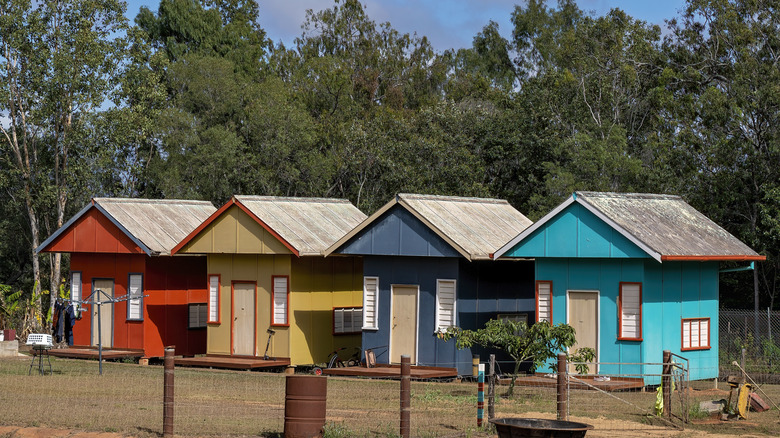 A row of multi-colored tiny rooms in a rural area.