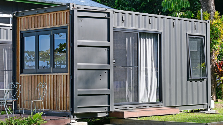 A container home with a window sitting in a yard.