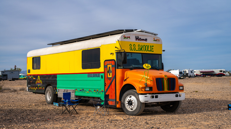 A multi-colored skoolie mobile home conversion in a desert.