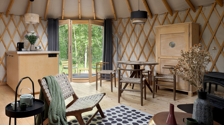 A yurt decorated with honey-colored wooden furniture.