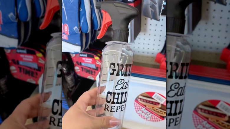 A hand holds a spray bottle with measuring marks and the words Grill Eat Chill Repeat printed on it.