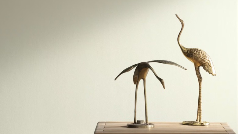 Bird figurines sitting in front of an off white wall.