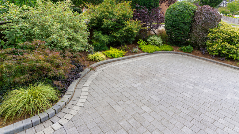 Shrubs and grasses surround a driveway edged with block pavers