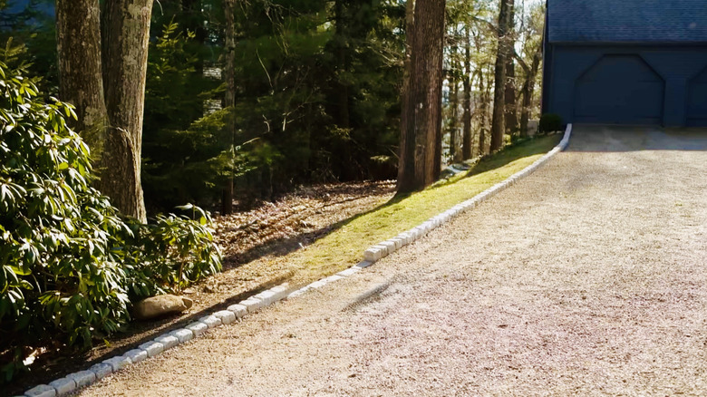 Cobblestones line a driveway in a wood area.