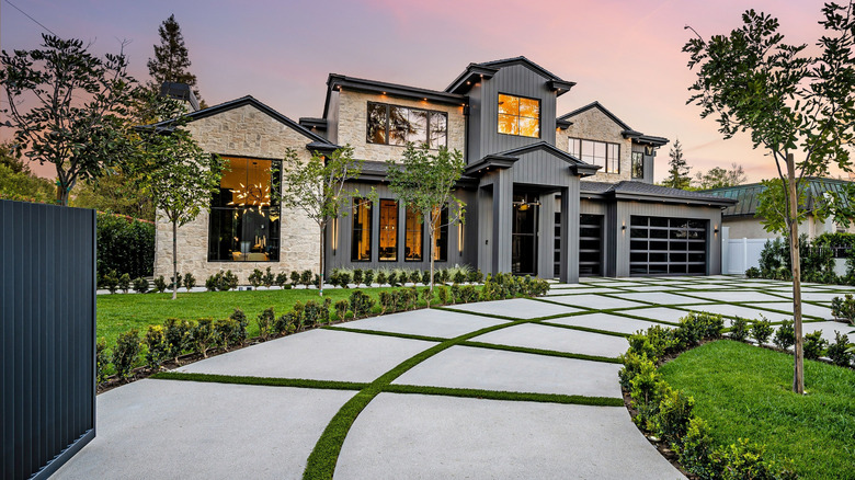 Well-landscaped driveway leads up to elegant home.