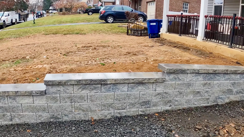A retaining wall borders a driveway in front of a home.