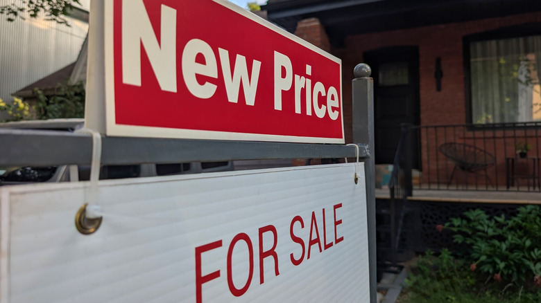 New price sign above for sale sign in front of house