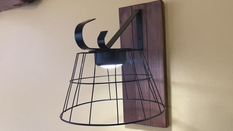 Wall light fixture made with a Dollar Tree wire basket attached to a wood backer with a metal hanger