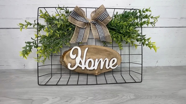 Dollar Tree wire basket used as a wall hanging with artificial greenery, a bow, and a home sign