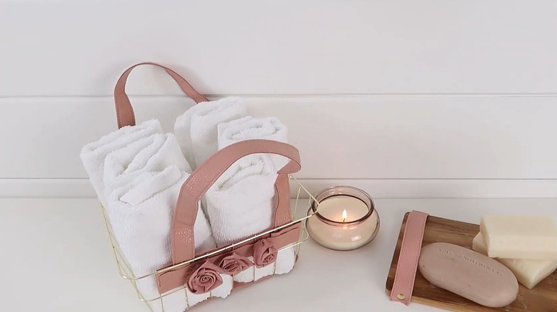 Wire Dollar Tree basket with leather strap embellishments holding folded hand towels