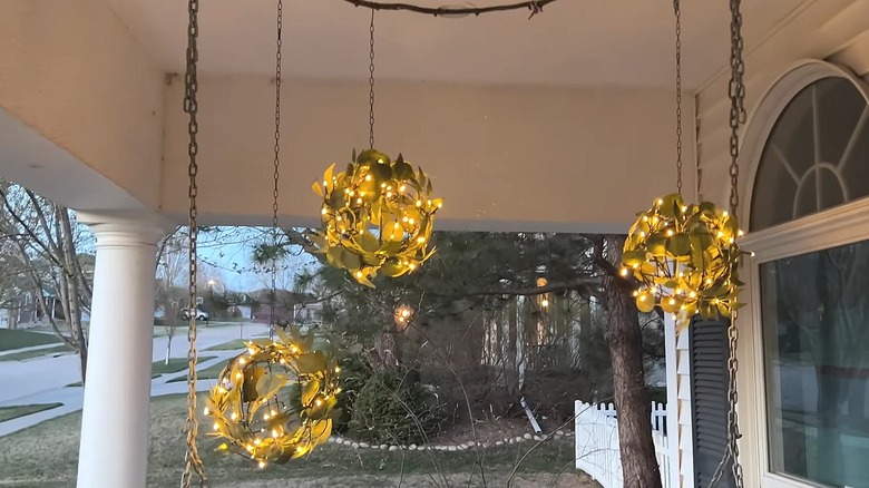 Three glowing orbs made from Dollar Tree wire baskets hanging on a porch
