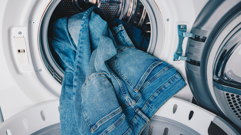 Blue denim jeans hanging out of a washing machine