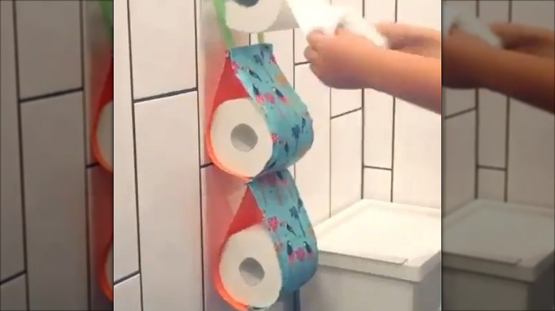 A fabric sling holder with rolls of toilet paper