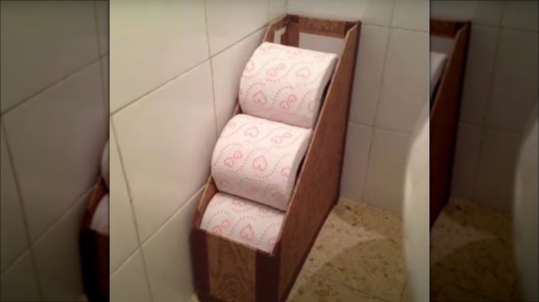 A file holder in a corner with extra toilet paper rolls
