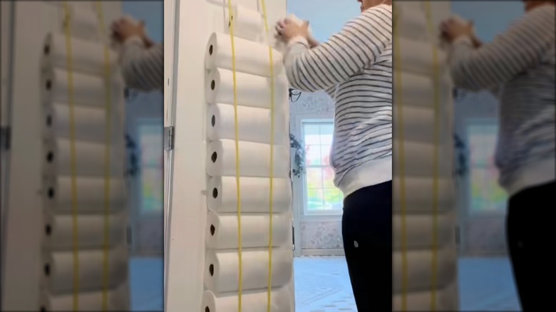 A person adding paper towels to inside of door