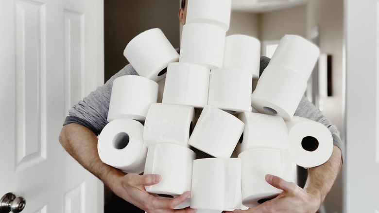 Person balancing multiple toilet paper rolls