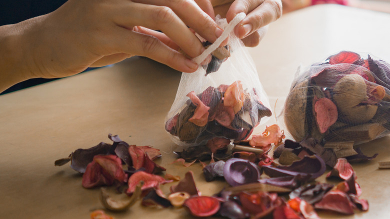 Hands making potpourri out of mesh laundry bags and dried flower petals