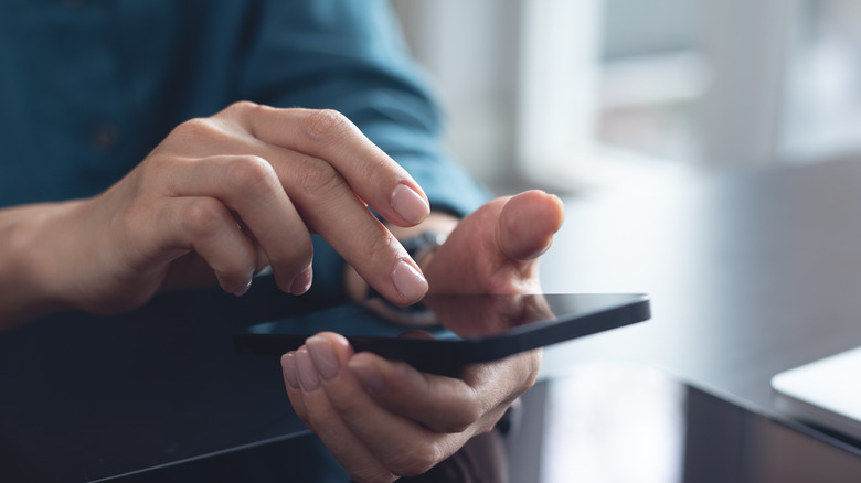 A finger tapping the screen of a cell phone.