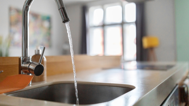 A sink faucet with water pouring out.