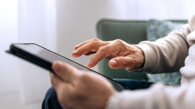 Senior sitting on a couch using a tablet.
