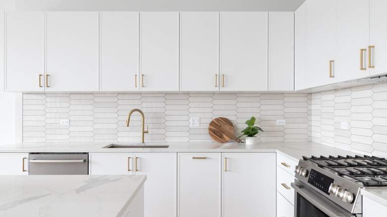 A kitchen with white backsplash, counters, and cabinetry